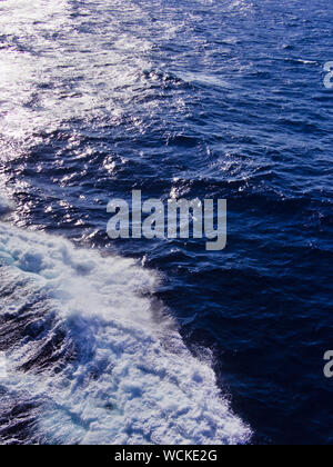 Acqua di mare schiuma formata dalla nave in movimento e la riflessione alla luce del sole. Foto Stock