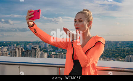 Il giovane bella donna di abbigliamento sportivo in piedi sul tetto di un grattacielo in una città. Bella ragazza guardando il panorama della città in piedi su un b Foto Stock