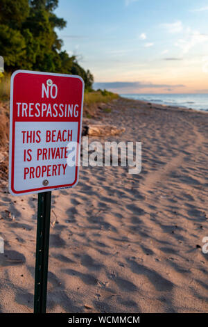Unione Pier, Michigan - un segno mette in guardia contro la trasgressione su una spiaggia privata sulla riva del lago Michigan. Foto Stock