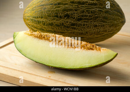 Pezzo di Piel de Sapo melon e sementi da vicino con un intero uno in background Foto Stock