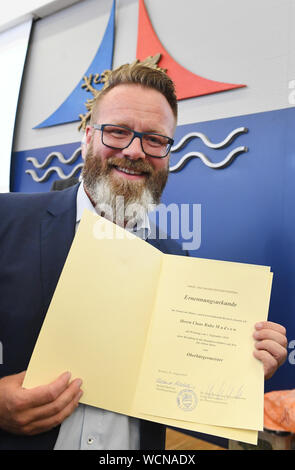 Rostock, Germania. 28 Agosto, 2019. Il danese Claus Ruhe Madsen (non-partito) mostra il suo certificato di nomina come sindaco presso la cittadinanza incontro in municipio. Egli è il primo sindaco di una grande città con più di 200.000 abitanti senza un passaporto tedesco. Madsen vuole spostare nel suo ufficio il 09/02/2019. Credito: Stefan Sauer/dpa-Zentralbild/dpa/Alamy Live News Foto Stock