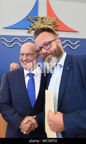 Rostock, Germania. 28 Agosto, 2019. Roland Methling (l-r), signore sindaco della città anseatica di Rostock e si congratula con il suo successore, Claus Ruhe Madsen dalla Danimarca, che è anche indipendente. Madsen è il primo sindaco di una grande città con più di 200.000 abitanti senza un passaporto tedesco. Madsen vuole spostare nel suo ufficio il 09/02/2019. Credito: Stefan Sauer/dpa-Zentralbild/dpa/Alamy Live News Foto Stock