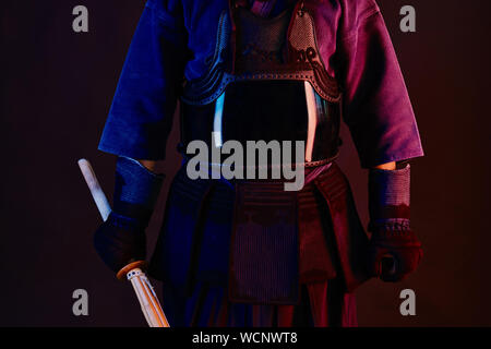 Immagine ravvicinata, Kendo fighter indossa in una corazza, kimono tradizionali è la pratica delle arti marziali con shinai spada di bambù, sfondo nero. Foto Stock