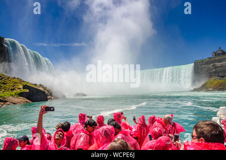 Turisti e visitatori di sperimentare la meraviglia naturale che è le Cascate del Niagara in un nuovo modo, da vicino e dall'acqua su una nave da crociera in Niagara Falls Foto Stock