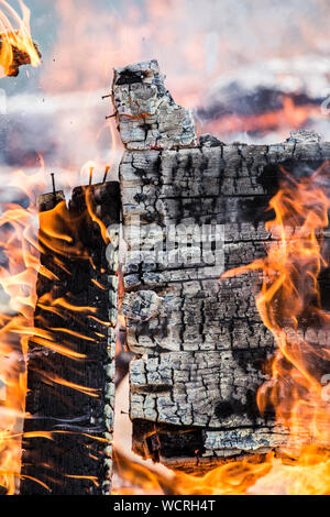 Vista in dettaglio della combustione di legno verniciato da muro caduto oltre, tanto fumo e fiamme e carbone. Home casa di fuoco concetto. Foto Stock