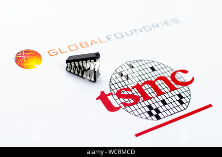 Fonderie globale vs. TSMC. Loghi stampati di aziende di semiconduttori e due microchip in forma di attaccare le ganasce. Foto concettuale. Foto Stock