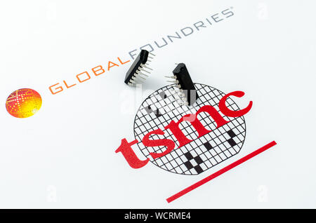 Fonderie globale vs. TSMC. Loghi stampati di aziende di semiconduttori e due chip - uno in attacco e uno a difendere la posizione. Foto concettuale. Foto Stock