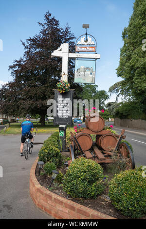 Il Woolpack pub o Public House nel Surrey villaggio di Elstead, Regno Unito, con un ciclista dal segno di pub Foto Stock