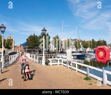 Madre e figlia a piedi sul ponte pedonale su noorderhaven nella città olandese di Harlingen Foto Stock
