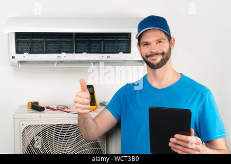 Servizio di installazione di fissare la riparazione manutenzione di un condizionatore di aria unità interna, da cryogenist tecnico lavoratore dando Thumbs up ready per andare dopo comm Foto Stock