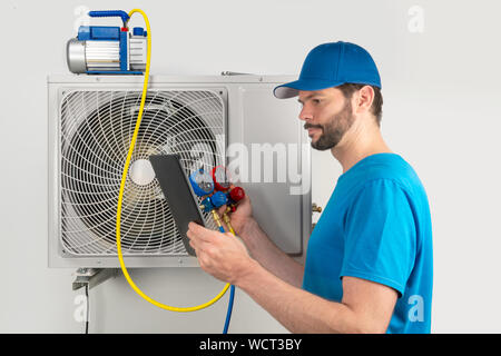 Servizio di installazione di fissare la riparazione manutenzione di un condizionatore di aria unità esterna, da cryogenist tecnico lavoratore evacuare il sistema con pompa per vuoto a Foto Stock