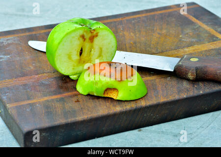 Mela tagliata aperta con un marcio area sul tagliere di legno con il coltello Foto Stock