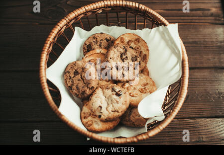 Biscotti al cioccolato risiede in un cesto di vimini. Un cestello con senza glutine i cookie su un tavolo di legno. Messa a fuoco selettiva. Foto Stock