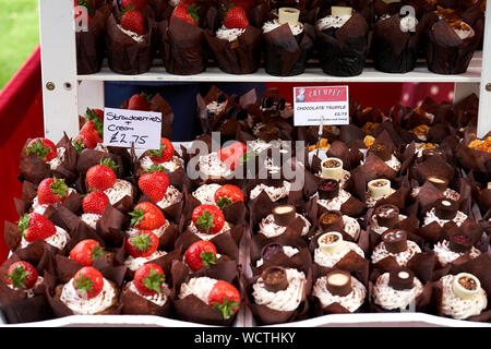 Foto di fragole e panna e ricca di tartufo al cioccolato muffin a un mercato in stallo. Foto Stock