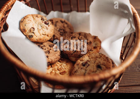 Biscotti al cioccolato risiede in un cesto di vimini. Un cestello con senza glutine i cookie su un tavolo di legno. Messa a fuoco selettiva. Foto Stock