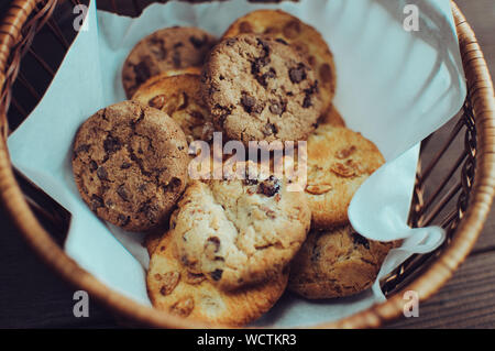 Biscotti al cioccolato risiede in un cesto di vimini. Un cestello con senza glutine i cookie su un tavolo di legno. Messa a fuoco selettiva. Foto Stock