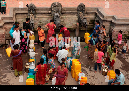 La scarsità di acqua potabile pura è acuto in Patan nonché a Kathmandu. Persone stare in piedi per ore a riempire le loro benne e contenitori di plastica da La Pietra Antica o beccucci hitis. Patan, Nepal. 2010. Foto Stock