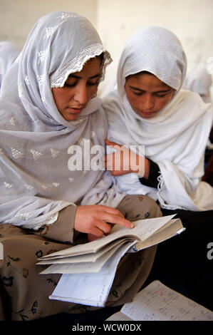 Due ragazze studio dal loro libro di testo. Bam Sarai governo scuola primaria, centrale Provincia di Bamyan, Afghanistan. Maggio 12, 2009. Foto Stock