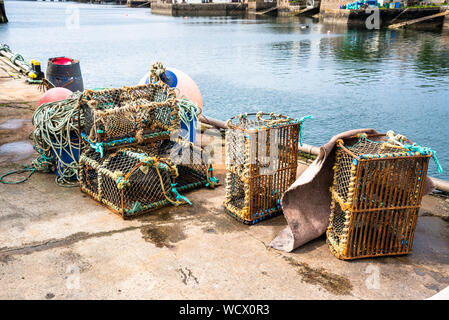 Rusty Lobster Pot con vecchie funi e boe sulla banchina del porto di pesca Foto Stock