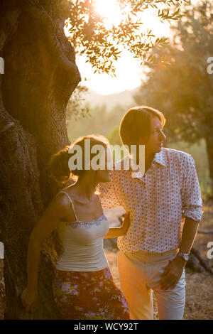Mid-adulto giovane appoggiato su di un albero al tramonto. Foto Stock