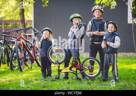 Bambini meccanica, riparazione di biciclette. Contenti i bambini che fissa bike insieme all'aperto nella giornata di sole. Riparazione di biciclette concept. Il lavoro di squadra famiglia in posa con strumenti Foto Stock