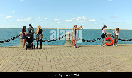 I visitatori di Voinovich Park sul porto Northcoast in Cleveland, Ohio, Stati Uniti d'America stand accanto al lago Erie durante la tarda estate tempo caldo. Foto Stock