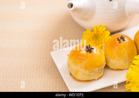 Mid-Autumn Festival del cibo tradizionale concetto - taglio bella torta della luna blu sulla placca modello su sfondo bianco con fiore, close up, spazio di copia Foto Stock