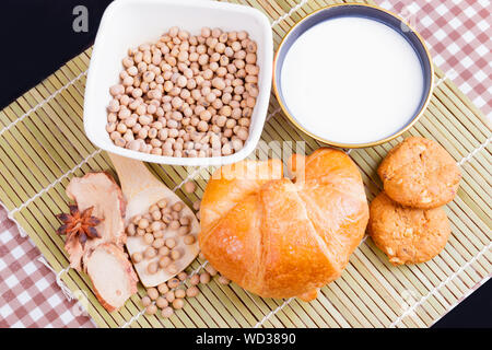 Croissant pane cotto con il latte nella tazza di fagioli di soia in tazza di cookie e spezie in legno di bambù. copia spazio per testo. vista superiore Foto Stock