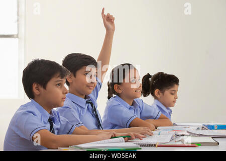 Ragazzo scuola chiedendo un dubbio nella classe Foto Stock