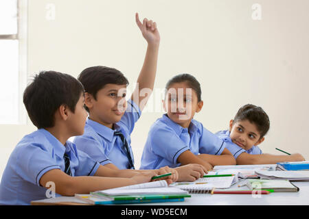 Ragazzo scuola chiedendo un dubbio nella classe Foto Stock