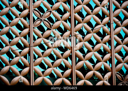 Ravvicinata di un rivestimento metallico su blu edificio di vetro esterno con motivi floreali di ripetizione dei motivi geometrici e di forte dettaglio come sfondo astratto Foto Stock