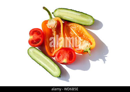 Verdure a fettine i cetrioli, peperoni e pomodori rosso verde giallo arancione in gocce di acqua su sfondo bianco isolato vista superiore Foto Stock