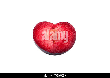 Mezza susina nella forma di un cuore rosso interno con una pietra su uno sfondo bianco isolato da vicino Foto Stock