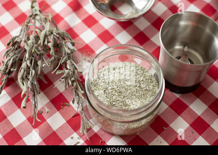 Vaso di vetro contenenti erbe aromatiche - come essiccata la salvia e il rosmarino - mescolato con sale di mare utilizzando un frullatore, un condimento fatti in casa per la cucina quotidiana Foto Stock
