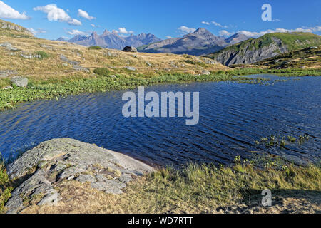 La sponda del lago Guichard sul Col de la Croix de Fer, con le Aiguilles d'Arves in background Foto Stock