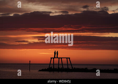 Il sole sorge sulla scultura " La Coppia " da artista Sean Henry, a Newbiggin-per-il-mare in Northumberland. Foto Stock