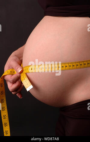 Donna incinta misurando il suo addome Foto Stock