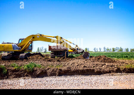 Grande escavatore è il riempimento di un dumper con terreno in corrispondenza del sito di costruzione, il progetto in corso. Foto Stock