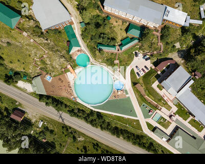 Vista aerea di un turista un centro ricreativo con tre piscine in legno e sedie a sdraio sulla natura nelle montagne di Altai su una soleggiata giornata calda. Foto Stock