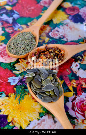 Cucchiai di legno con le spezie in su uno sfondo floreale Foto Stock