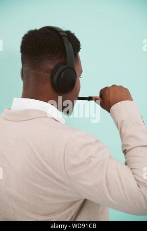 Colpo verticale di una persona afroamericana che indossa un beige camicia e cuffie nere Foto Stock