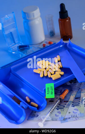 Contatore farmaceutica con capsule su, Rands Sudafricani in primo piano e bottiglie di medicazione, pillola cutter in background Foto Stock