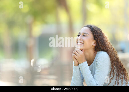 Felice di mixed-gara donna meditando seduto in un parco con spazio di copia Foto Stock