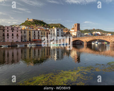 Città medievale Bosa durante il tramonto. Ponte e case colorate si riflette nel fiume Temo. Castello della città Foto Stock