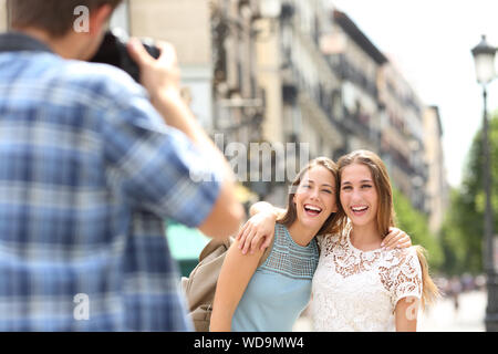 Tre turisti felici di scattare le foto con una reflex digitale durante una vacanza in una strada di città Foto Stock