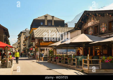 Vista sulla strada del centro di Chamonix-Mont-Blanc con le tipiche facciate di legno in una soleggiata giornata estiva con pochi turisti, Haute Savoie, Francia Foto Stock