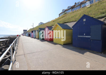 Pittoresca spiaggia di capanne lungo Sheringham lungomare in una giornata di sole con il blu del cielo. Foto Stock