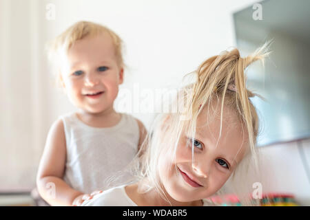 Carino adorabile bionda caucaian sorellina abbracciando il suo bimbo piccolo fratello.coppia di gemelli allegro giocando indoor. Ragazza carina e baby boy godere Foto Stock