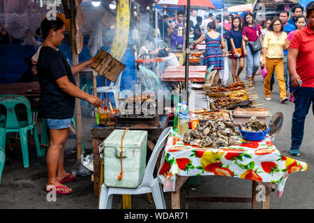 Filippino cibo di strada, una donna filippina la cottura della carne su un grill, Iloilo City, Panay Island, Filippine Foto Stock