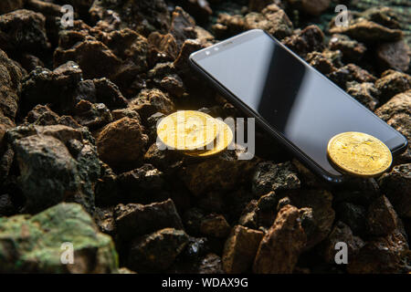 Smartphone e bitcoins. Bitcoin monete accanto allo schermo dello smartphone. Nella schermata smartphone grafico della crescita di valuta Foto Stock